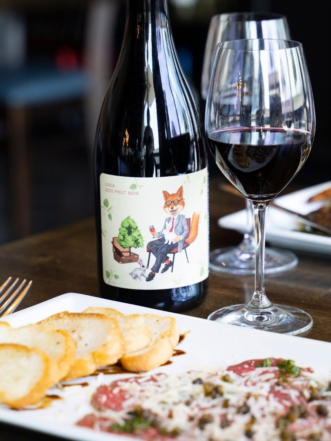 Beef carpaccio with capers and crostini beside a glass of Pinot Noir at D'Vine Wine Bar